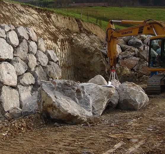 Large stone blocks piled beside an excavator